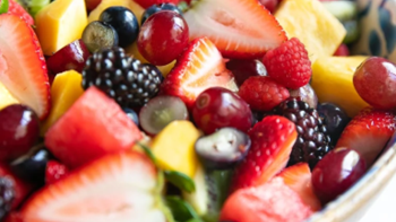 A close up of a bowl of fruits including strawberries, blueberries, blackberries, kiwi, grapes, and more. 