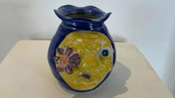 small ceramic vase with angry face and a flower in their eye
