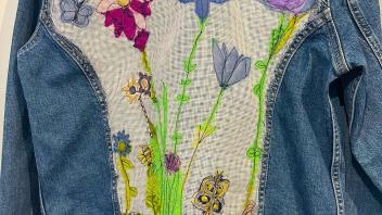 back of a jean jacket embellished with flowers and spring motif in stitches