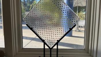 clear fused glass panel with rainbow dots in a metal stand