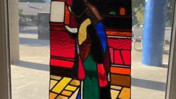 stained glass panel with a red background and a female form