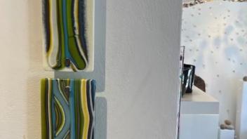 two fused glass panels mounted to the wall with green streaky motif