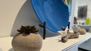 arrangement of faux ceramic rock with air plant and blue fused glass bowl in stand