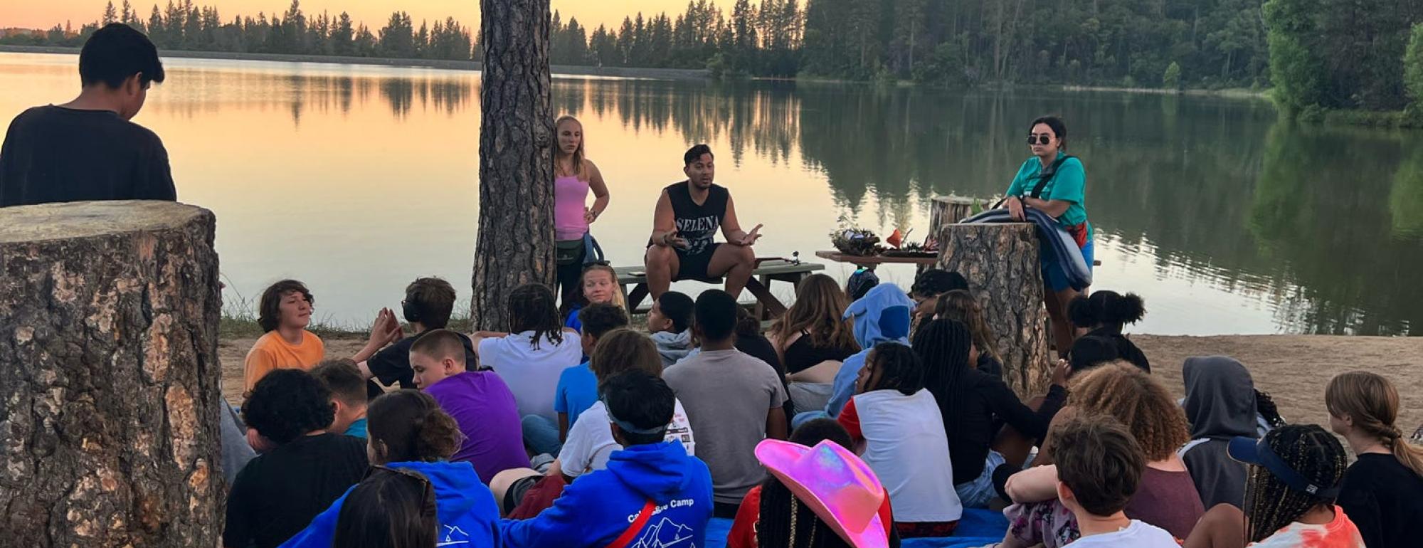 Campers outside at lake at sunset