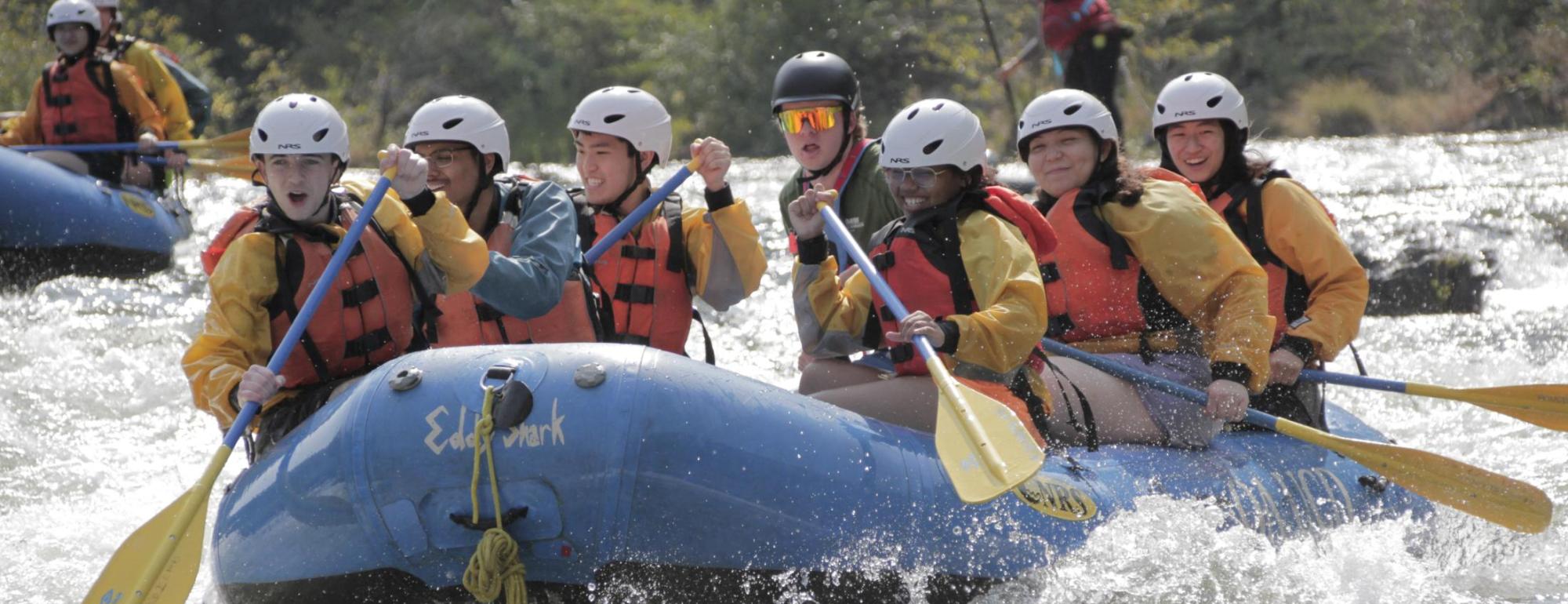 students whitewater rafting and laughing