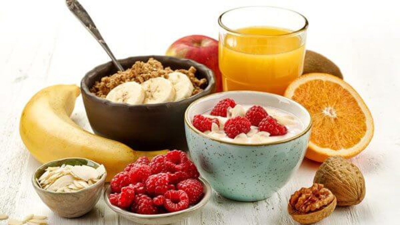 A collection of breakfast foods including bananas, a bowl of oatmeal, orange juice, and more.