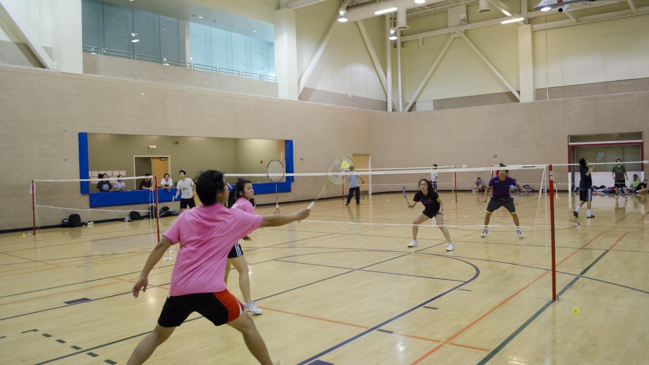 boy and girls playing badminton together in the gym