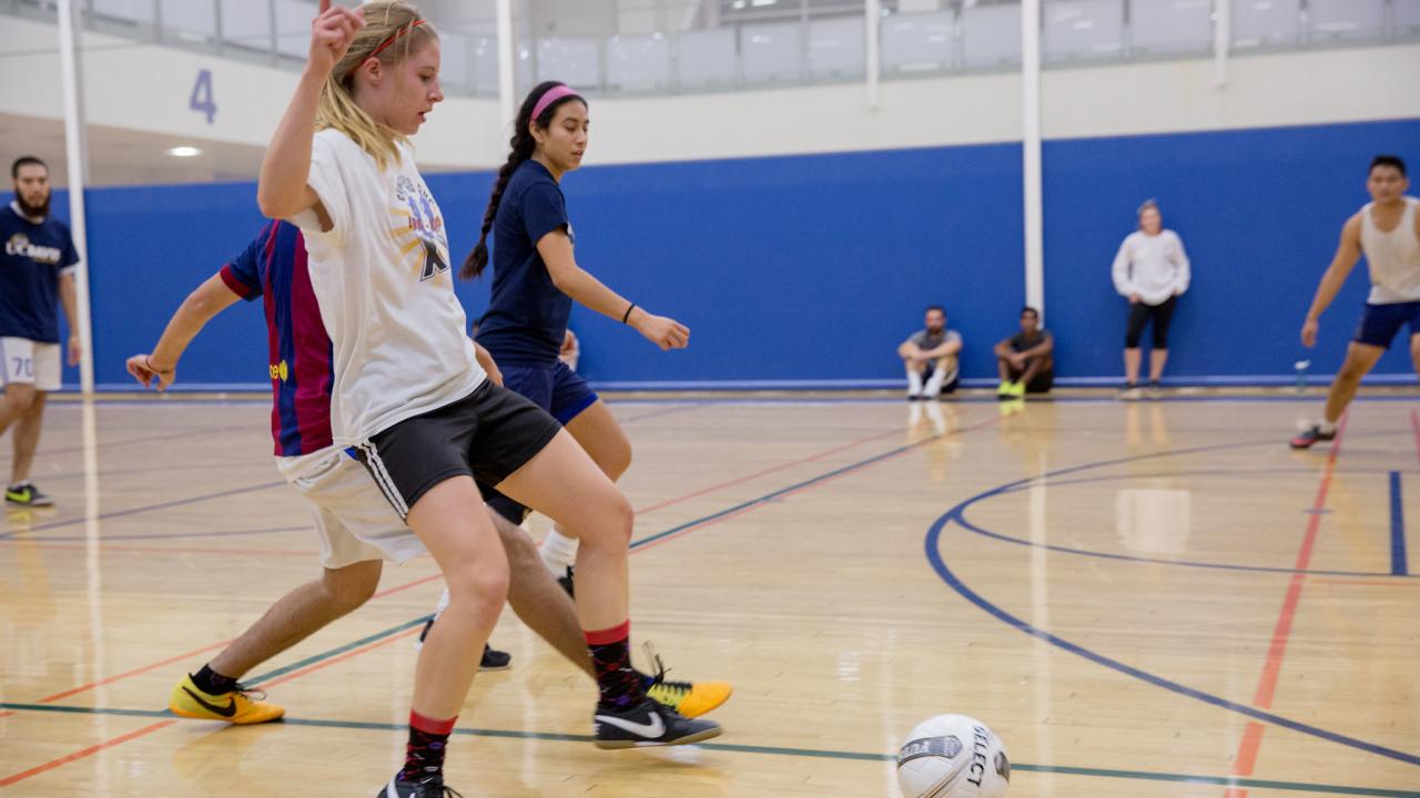 Boys and girls playing Futsal indoor soccer at a court in a gym