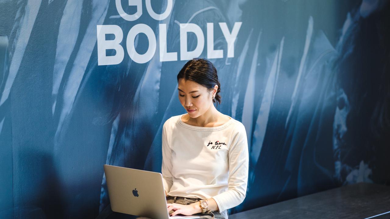 Girl sitting down on bench with her laptop
