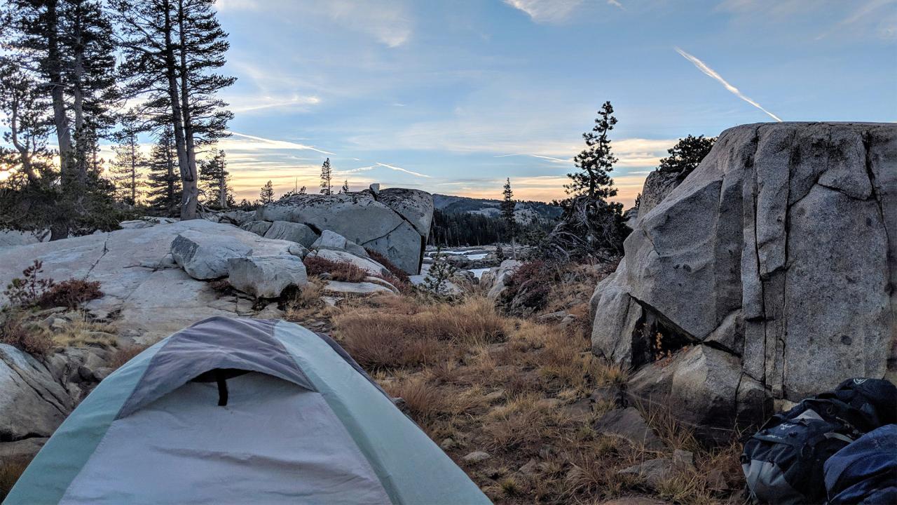 Tend in wilderness with several trees and boulders