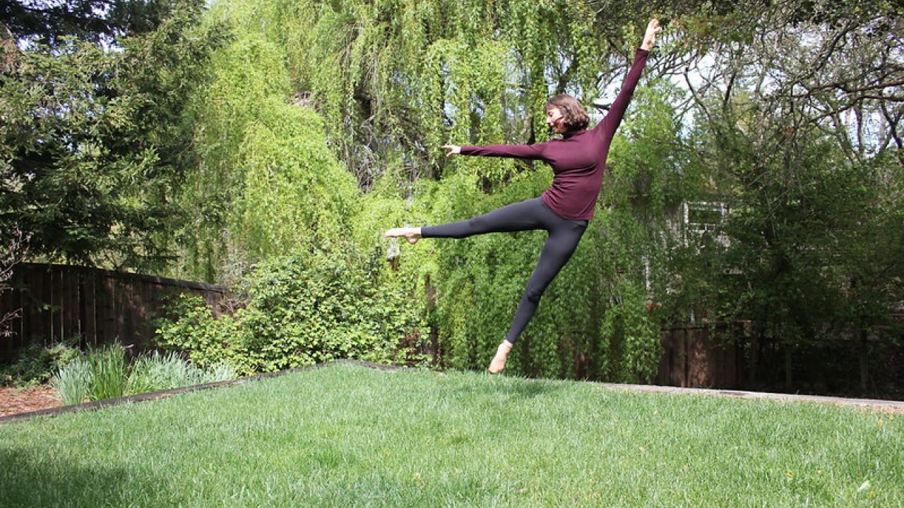 A dancer performing a leap in their backyard.