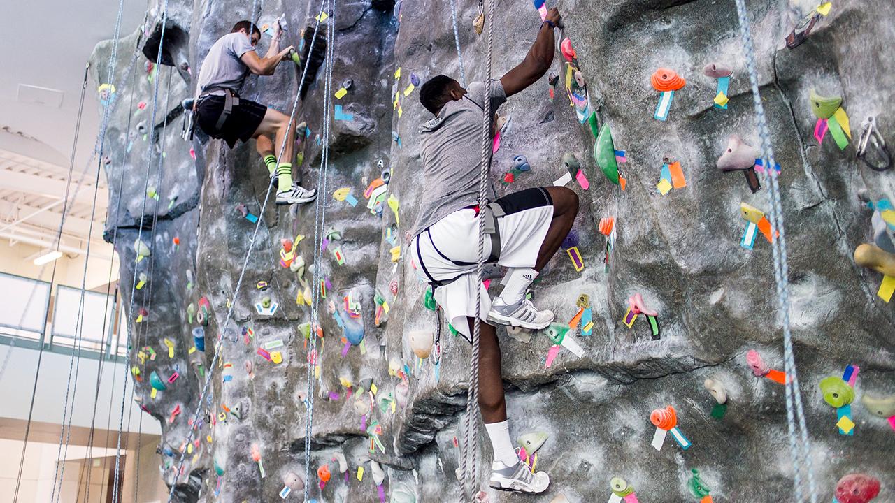 Two people climbing an indoor climbing wall at the ARC.