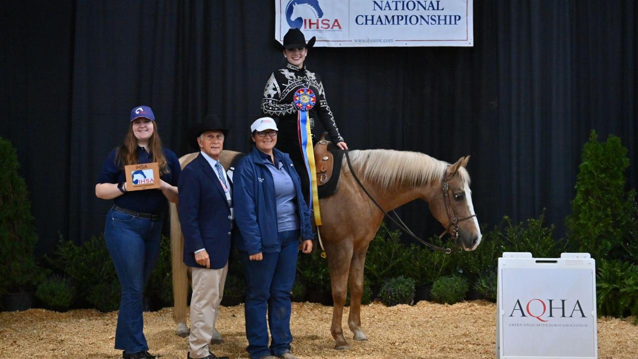 Rider in Western Uniform, sitting on horse, holding a championship ribbon. 
