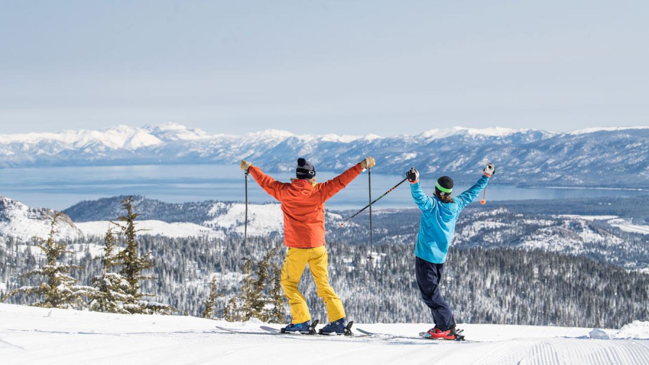 two people on skis standing on a snowy plain with their arms raised in the air