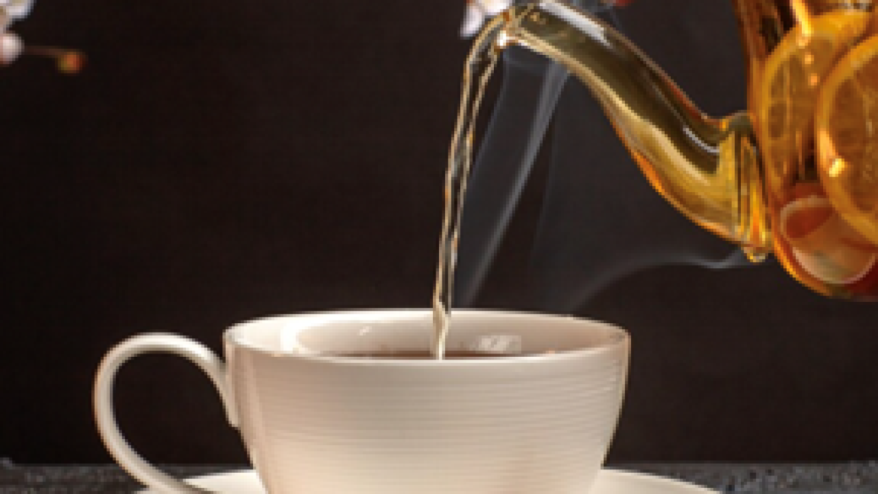 A teapot pouring liquid into a cup.