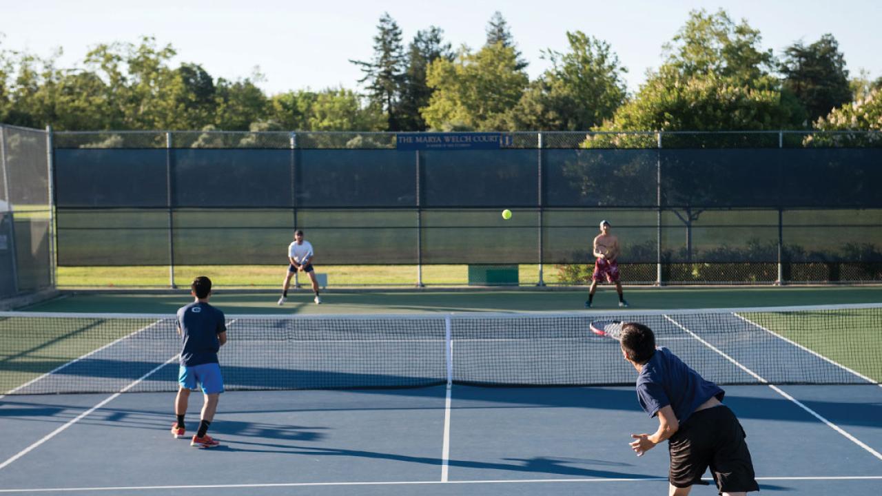 Students playing tennis on an outdoor court.