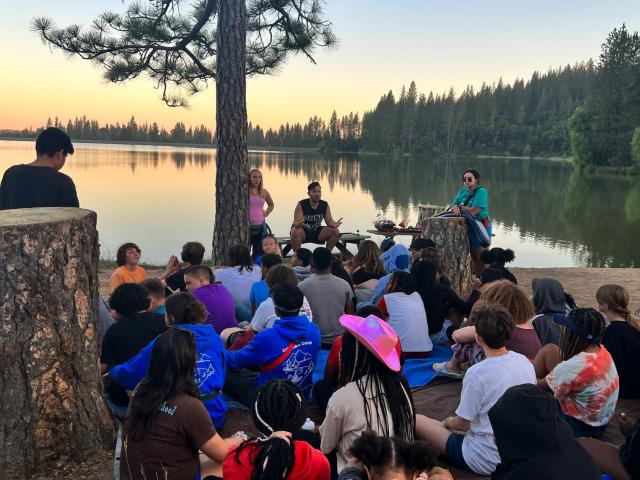 Campers outside at lake at sunset