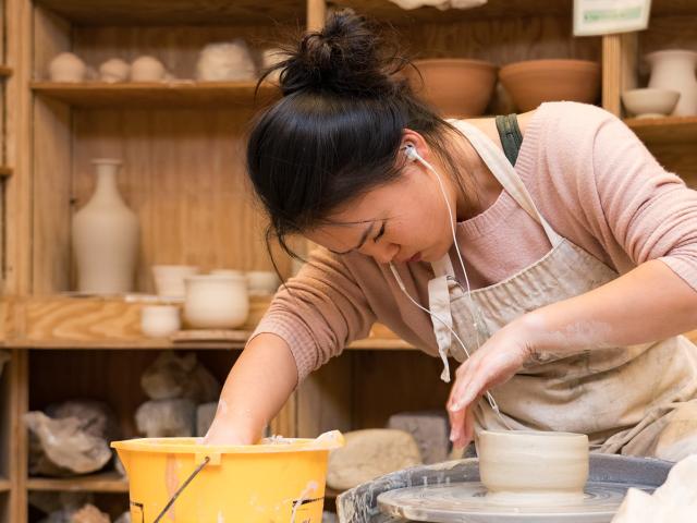 Woman shaping clay on a throwing wheel