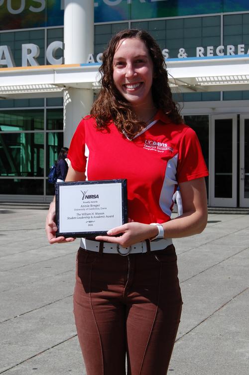 Annie Breger wears a red shirt and smiles in front of the Activities and Recreation Center