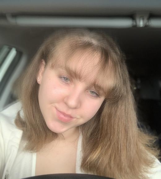 Rebecca smiles for the camera in her parked car.