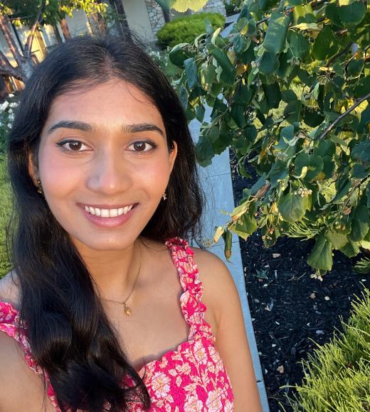 Neeraja stands next to a tree and smiles for the camera.