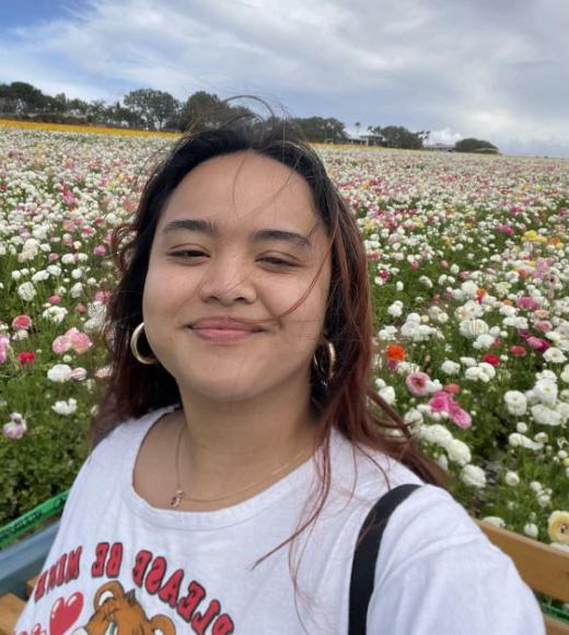 Kathlyn stands in front of a field of flowers and smiles for the camera.