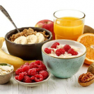 A collection of breakfast foods including bananas, a bowl of oatmeal, orange juice, and more.