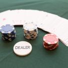 Picture of poker chips, cards, and dealer button on poker table