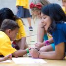 Camp counselor sitting with kids and drawing on the floor of a gym