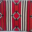 large quilt with geometric patterns of lines and triangles in red black and white