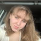 Rebecca smiles for the camera in her parked car. 
