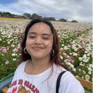 Kathlyn stands in front of a field of flowers and smiles for the camera.