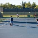 Students playing tennis on an outdoor court.