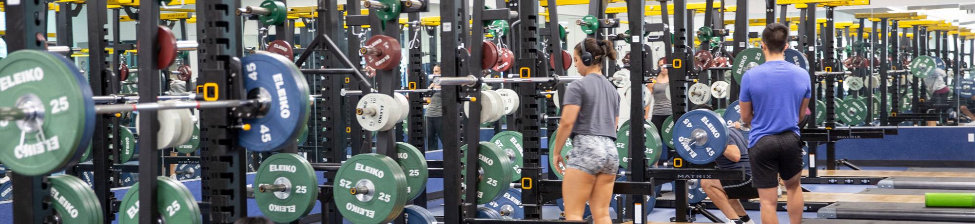 People walking around a gym weight room